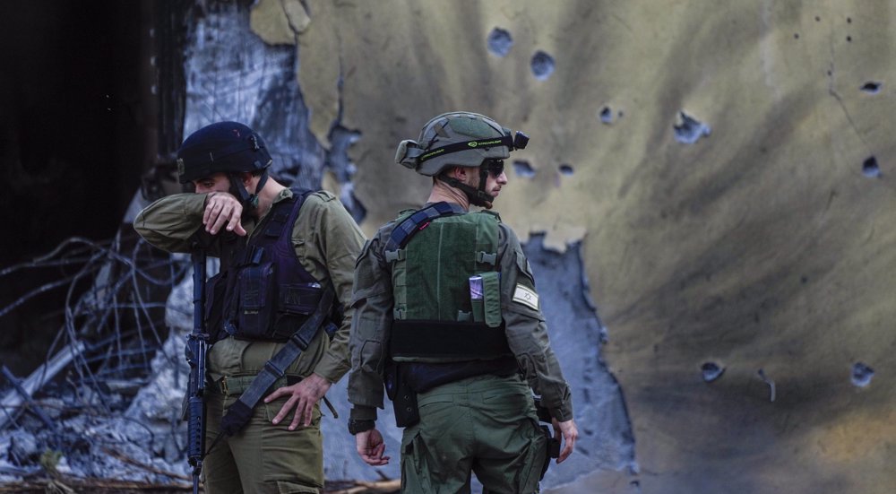 Des soldats israéliens passent devant des maisons détruites par des combattants du Hamas dans le kibboutz Be'eri, en Israël, le samedi 14 octobre 2023. (AP)