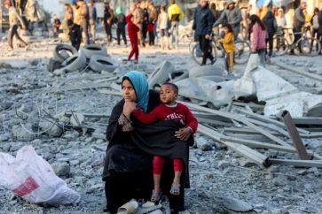 Une femme est assise avec un enfant sur le site d'un bombardement israélien sur un bloc résidentiel de la ville de Gaza le 14 janvier 2025. ©Getty Images
