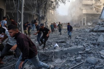 Des habitants se mettent à l'abri après une frappe israélienne qui a ciblé un bâtiment du camp de Bureij, dans le centre de Gaza, le dimanche 19 octobre 2025. ©AFP